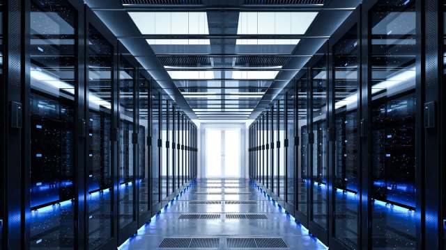 A modern data center hallway lined with black server racks and illuminated by blue lighting.