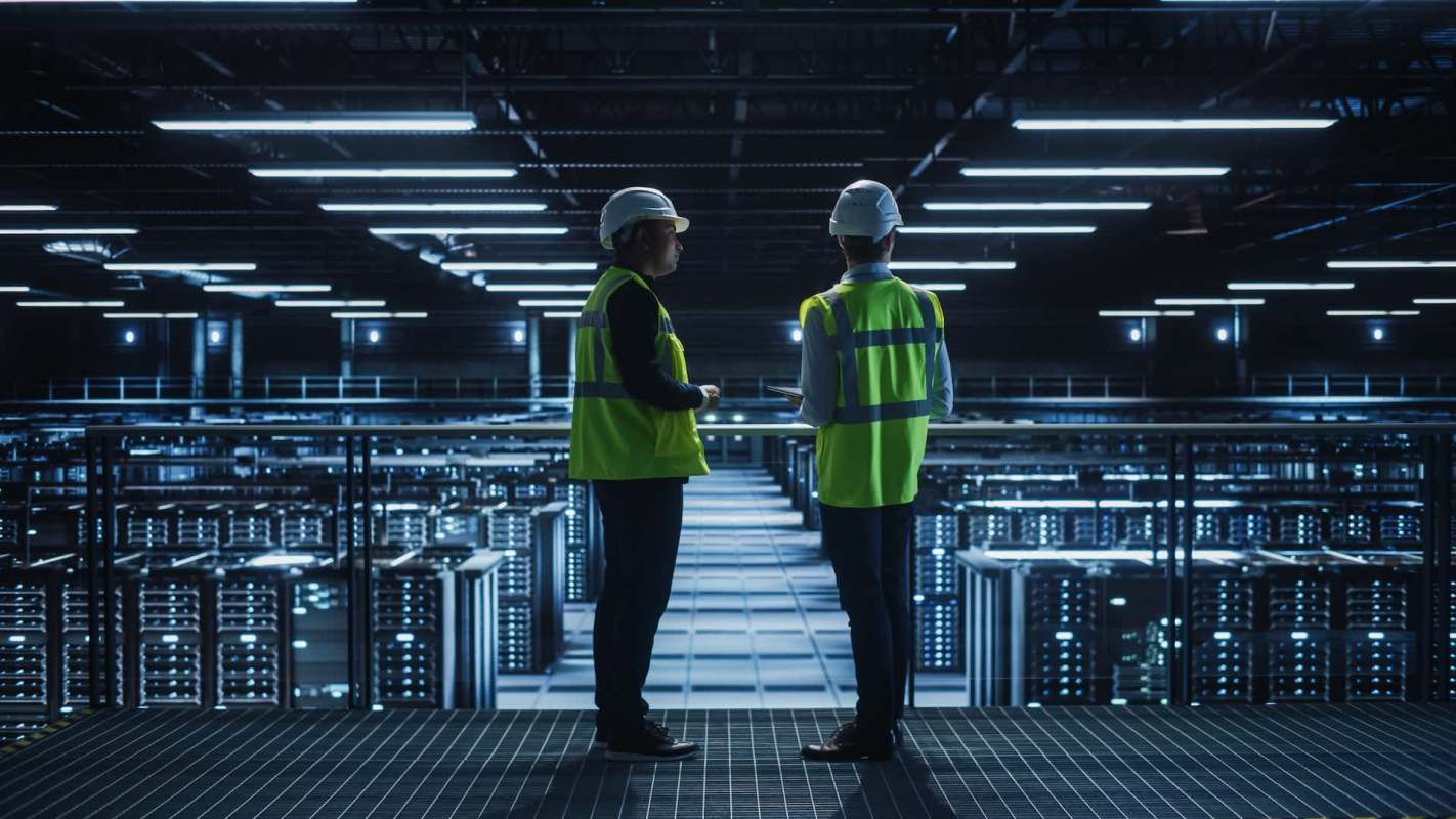Two workers in safety gear inside a data center.