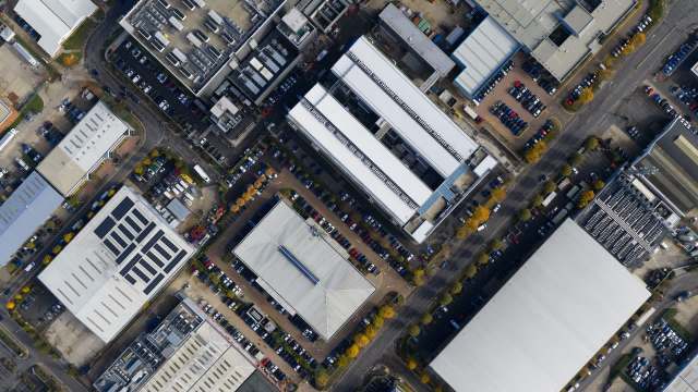 An aerial view of a commercial area featuring multiple buildings and parking lots filled with cars.