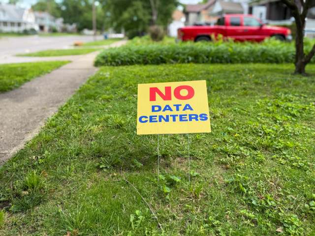 A yellow anti-data center sign in a yard.
