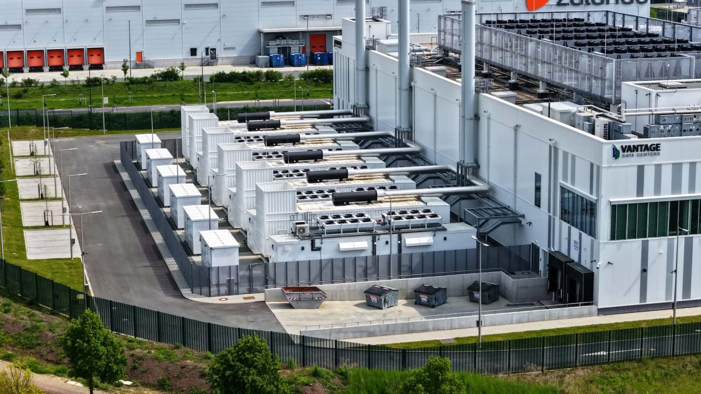 An aerial view of a modern data center featuring large cooling units and storage containers.