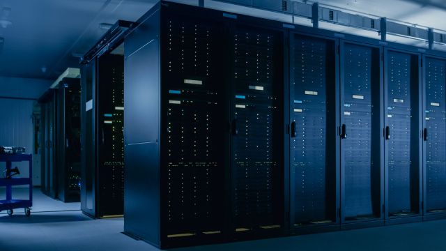 A dimly lit server room with rows of dark server racks.