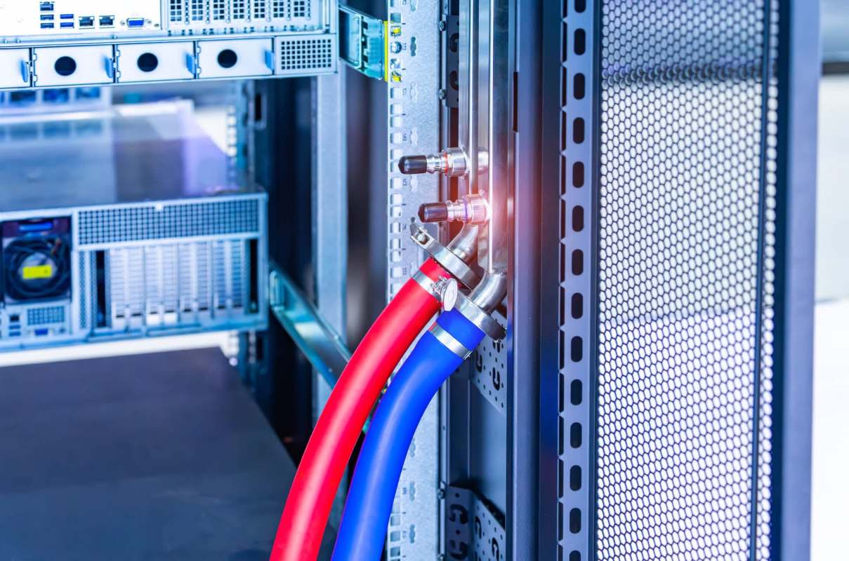 A close-up of red and blue hoses connected to a cooling system within a server rack.