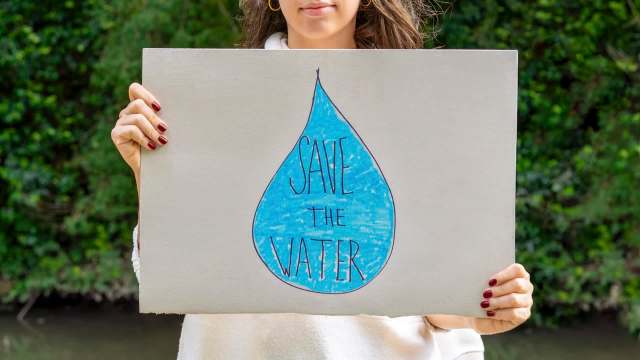 A person holding a "Save Our Water" sign.