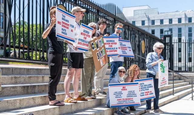 Protesters holding signs opposing tax breaks for data centers.