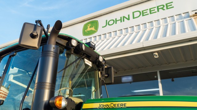 A John Deere tractor in front of a Deere company building.
