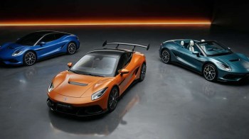 Three luxury sports cars in a showroom: an orange coupe, a blue coupe, and a teal convertible, all under dramatic lighting.