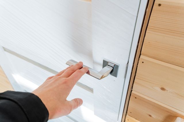 A person opening a white door.