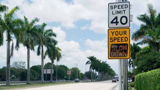 A speed limit sign and a digital warning to slow down.