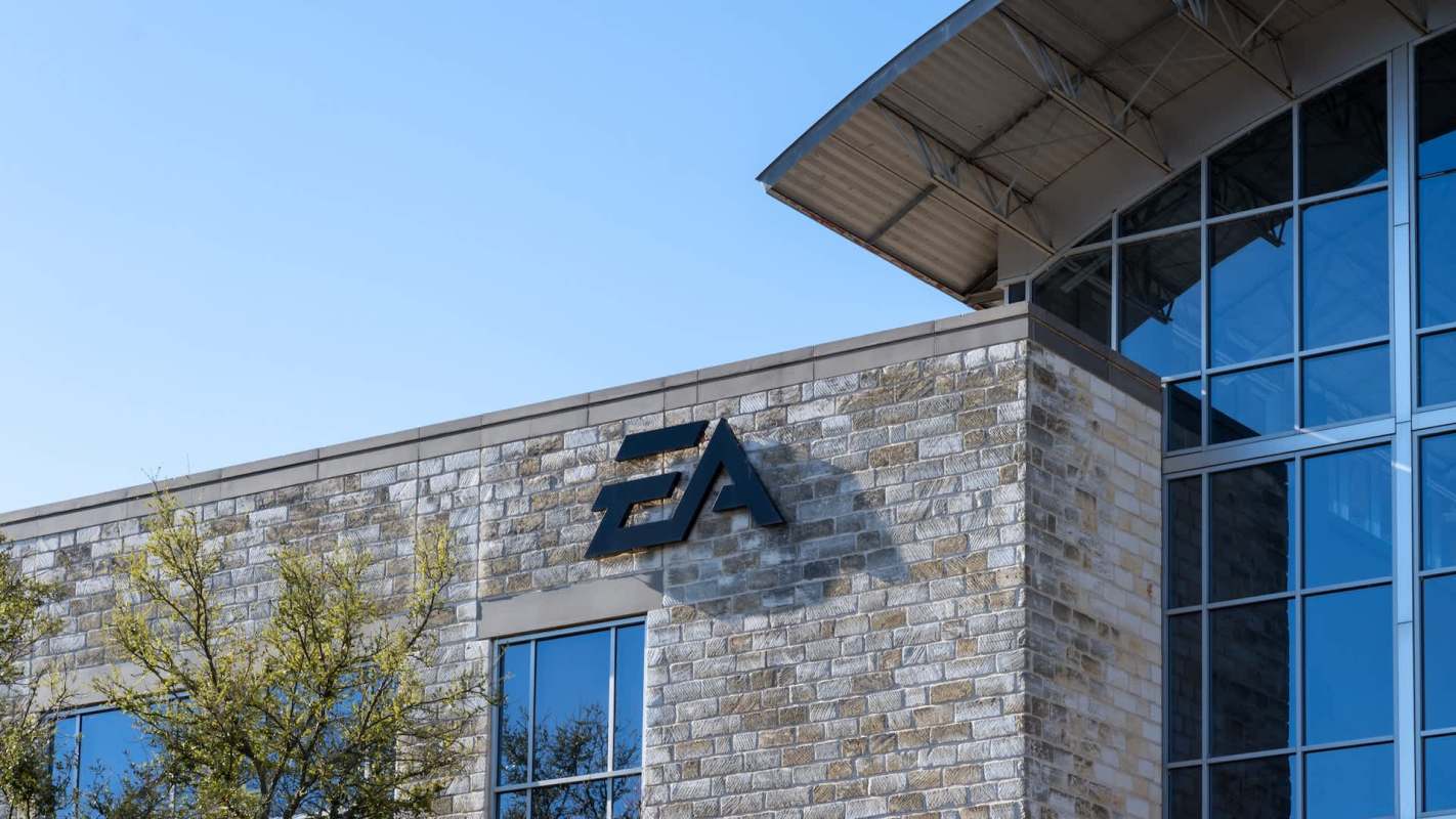 The exterior of a building featuring a large "EA" logo, with glass windows and stone walls.
