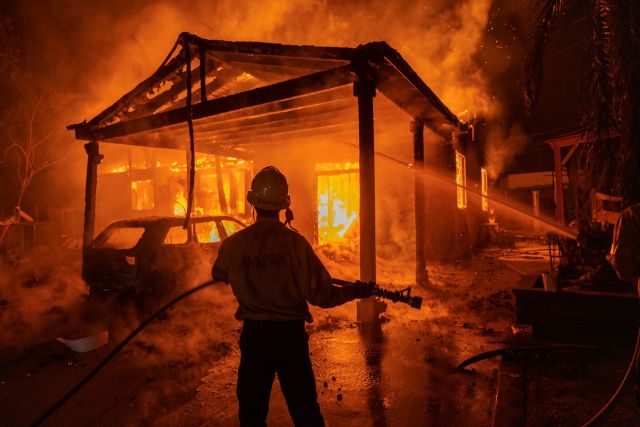 A firefighter standing in front of a burning home during the Eaton Fire.