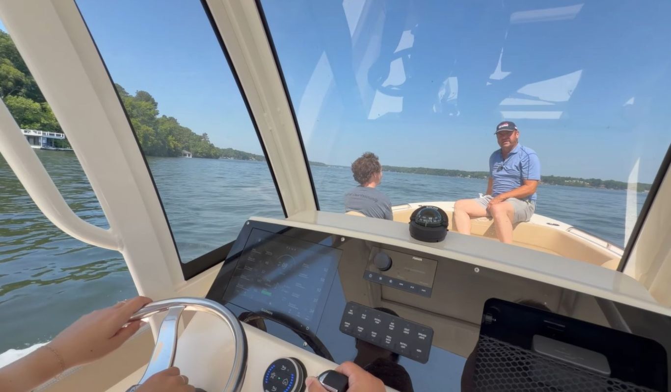Two people sitting on an electric boat as a third person steers.