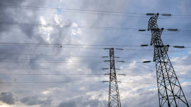 Two transmission towers against a cloudy sky.
