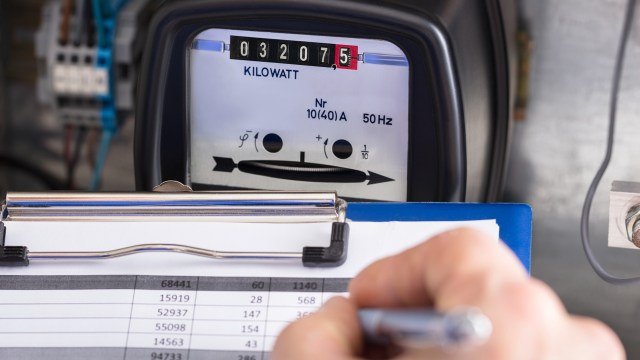 A technician recording electricity meter data on a clipboard.