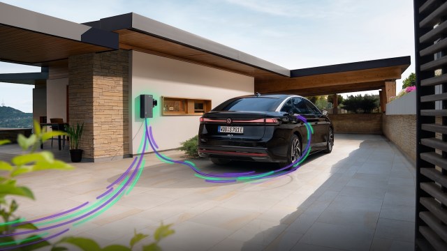 A black electric car is charging at a home charging station with green and purple lines representing charging.