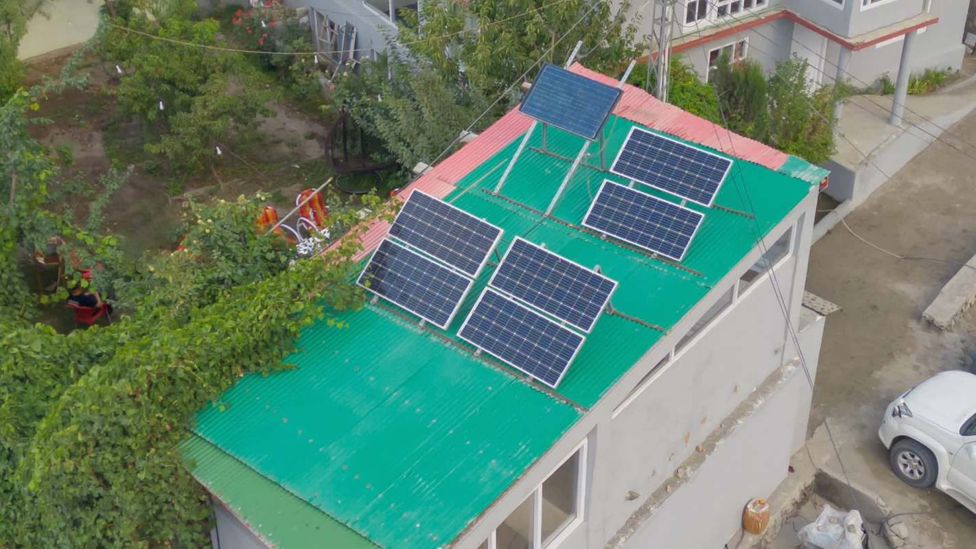 A green corrugated roof with solar panels on mounts.