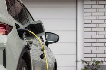 An electric vehicle is plugged in for charging in a garage setting.