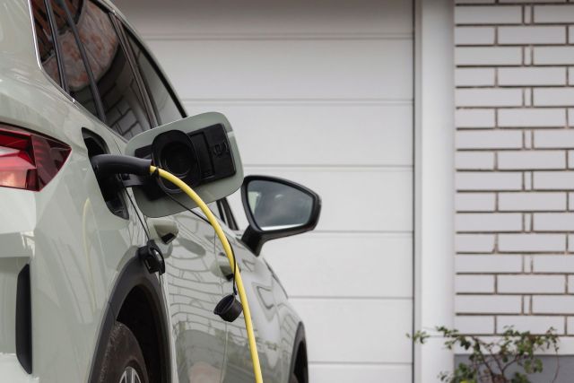 An electric vehicle is plugged in for charging in a garage setting.