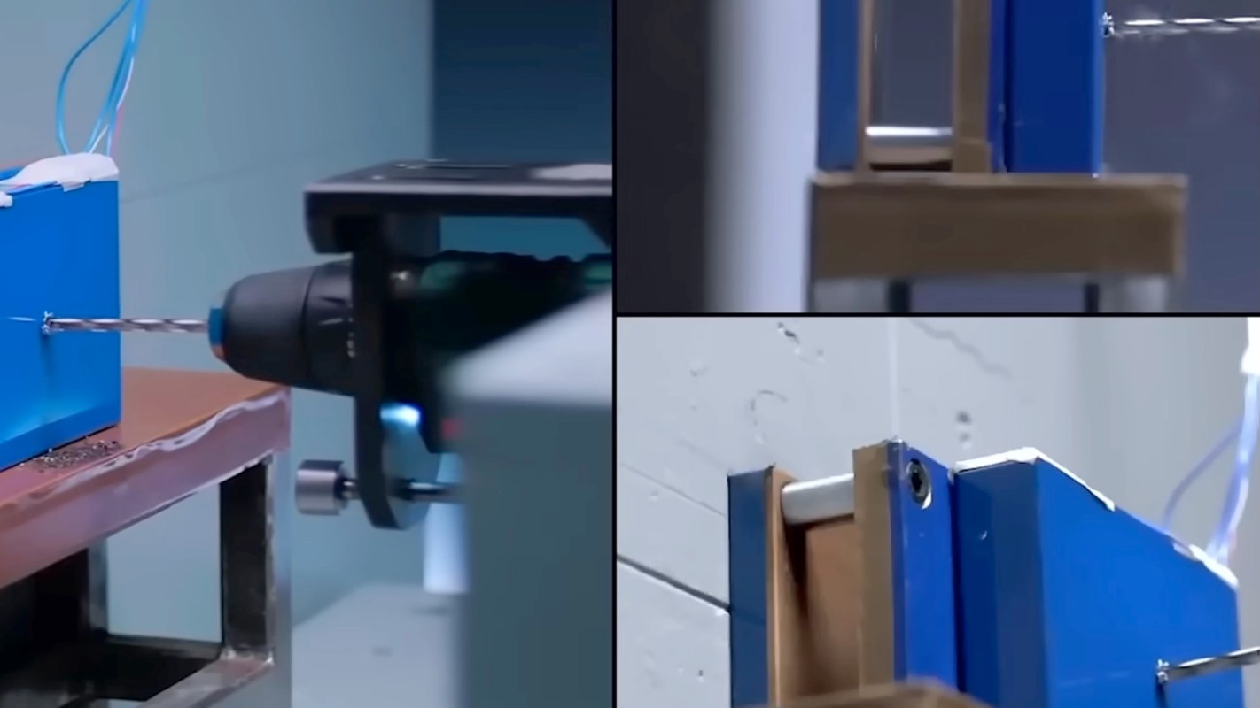A close-up view of a drill bit working on a blue equipment piece with various mechanical components.