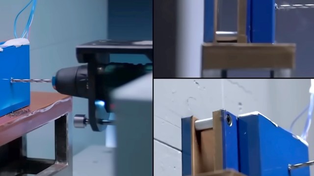 A close-up view of a drill bit working on a blue equipment piece with various mechanical components.