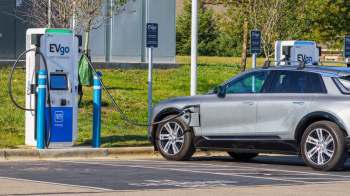 An electric vehicle is plugged into an EVgo fast charging station in a parking area.