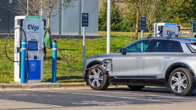 An electric vehicle is plugged into an EVgo fast charging station in a parking area.