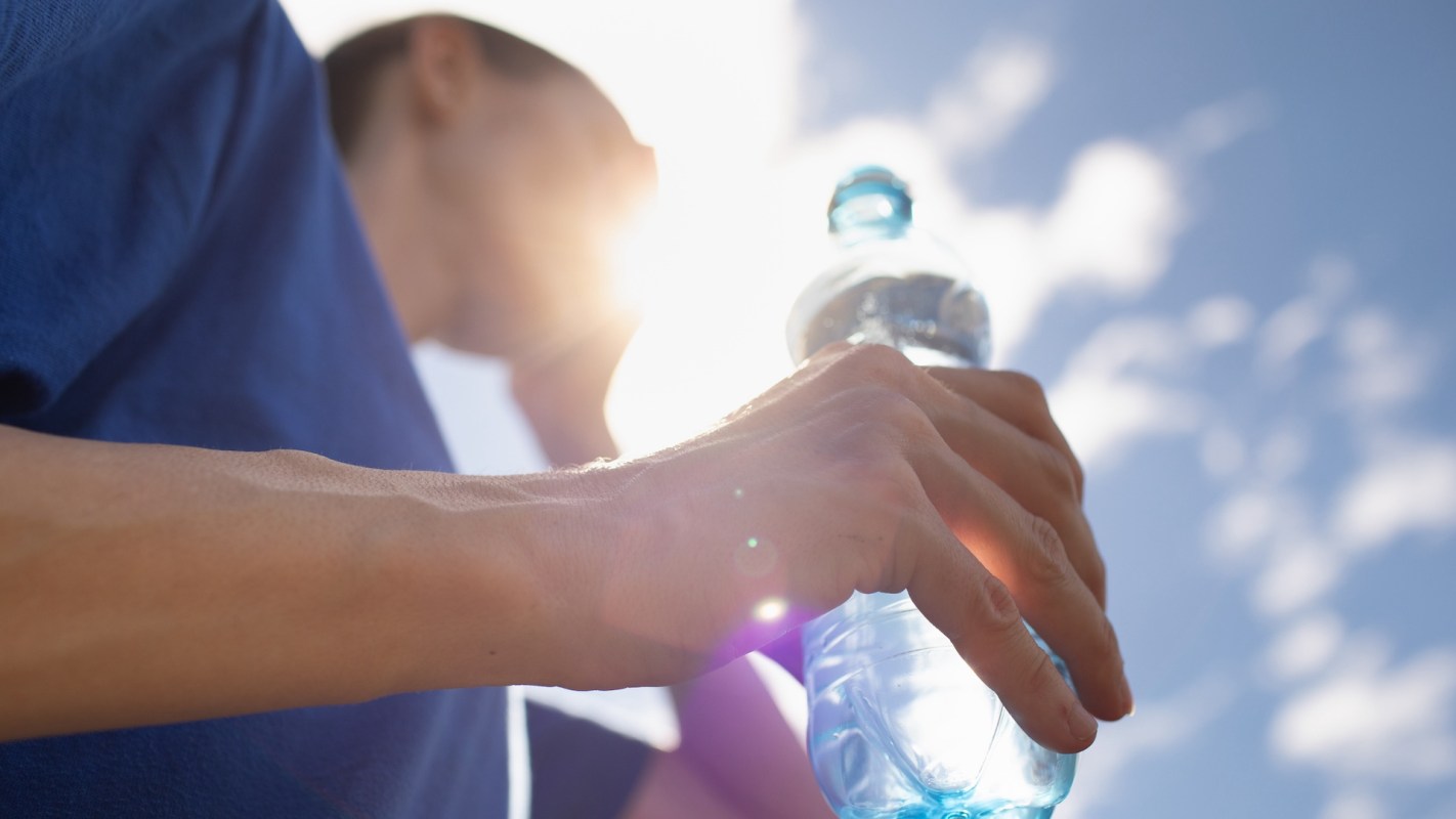 A person holding a water bottle on a hot, sunny day.