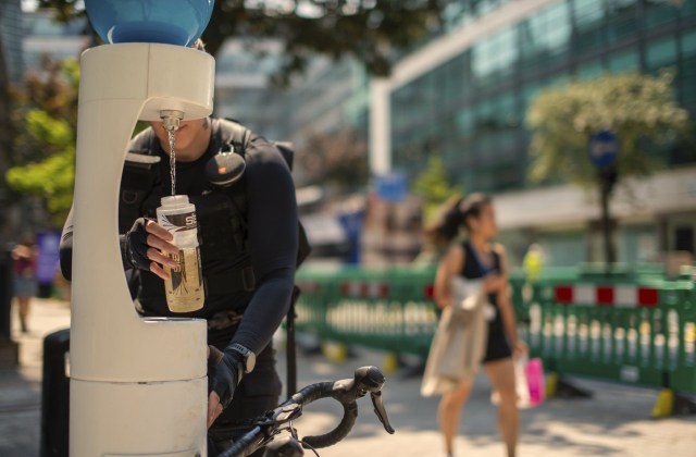 A person refills a water bottle on a hot day.