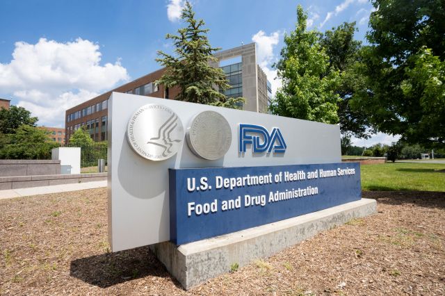 A sign for the U.S. Department of Health and Human Services Food and Drug Administration outside a modern building.