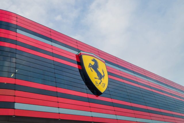 A close-up of a red and black striped building facade featuring a yellow Ferrari logo.