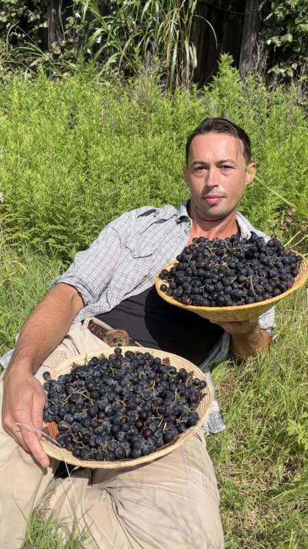A man holding two large bowls of grapes.