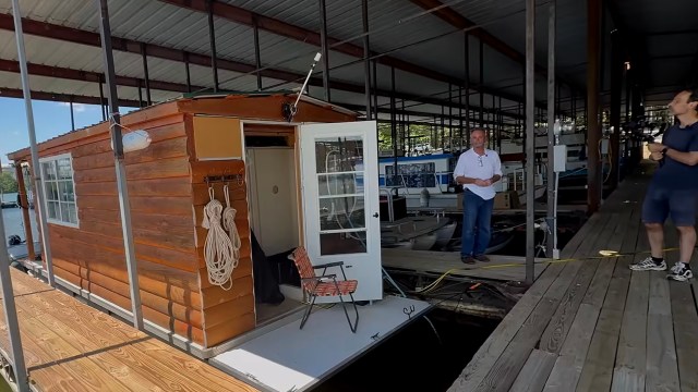 A wooden houseboat docked at a marina.