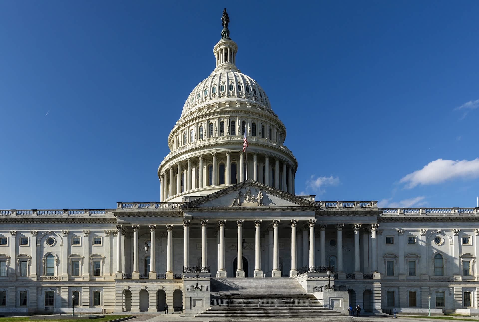 The U.S. Capitol building with its iconic dome and columns under a clear blue sky.