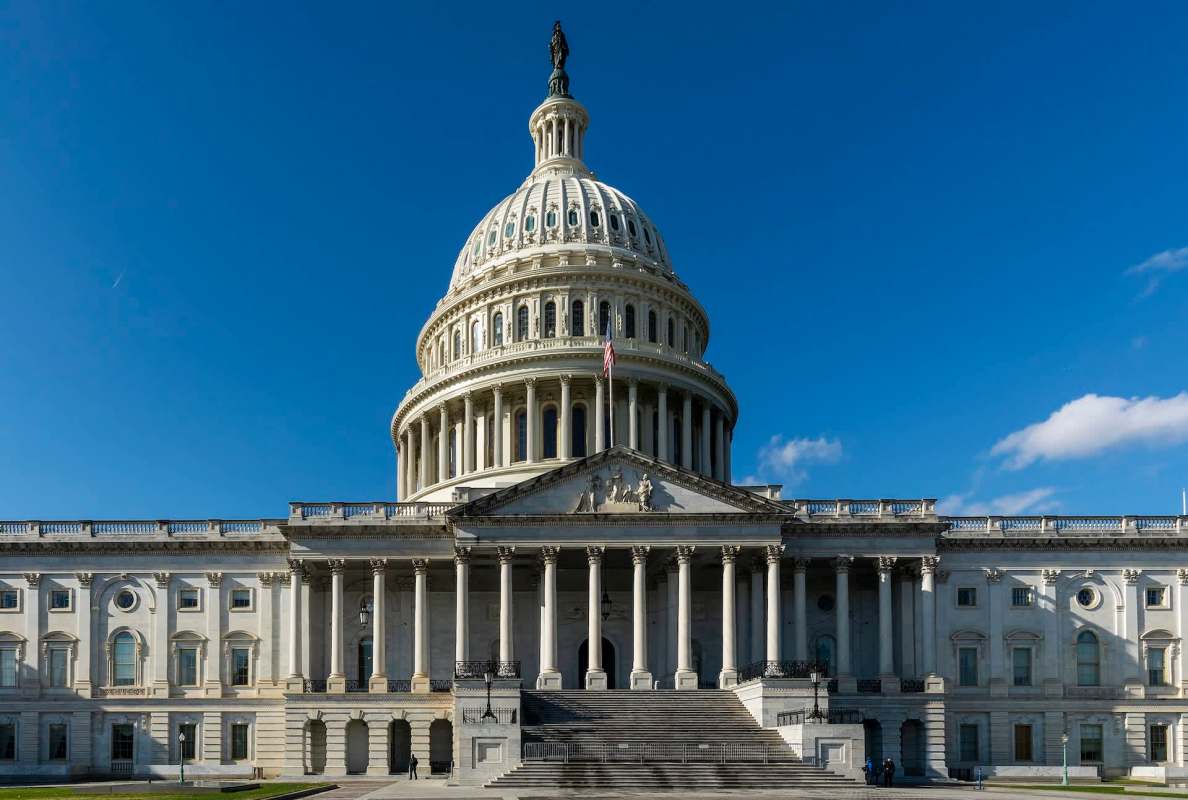 The U.S. Capitol building with its iconic dome and columns under a clear blue sky.
