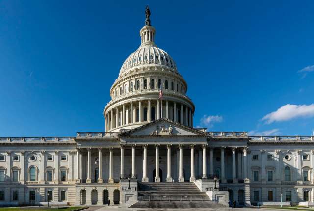 The U.S. Capitol building with its iconic dome and columns under a clear blue sky.