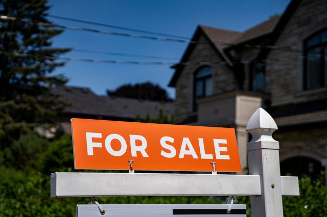 A "for sale" sign in front of a house.