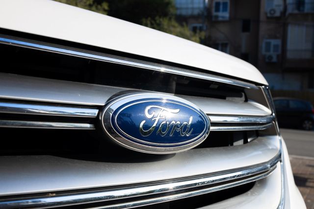 A silver car grille featuring the blue Ford logo.
