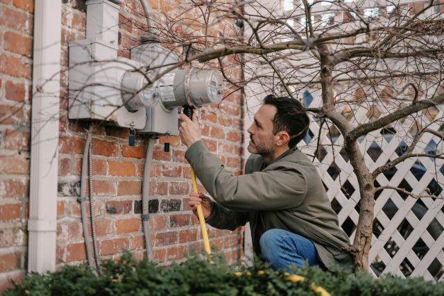 A man plugging a cord into a utility meter.
