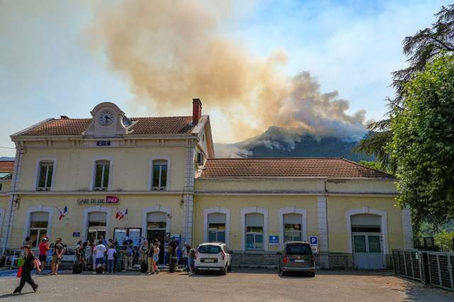 A wildfire on a mountain behind a train station.