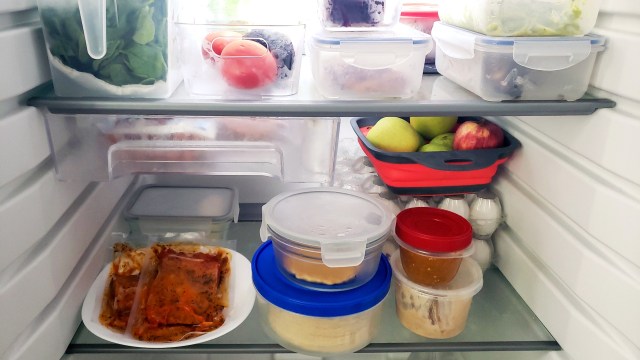 A refrigerator shelf filled with various food items in containers, including vegetables, fruits, and leftovers.