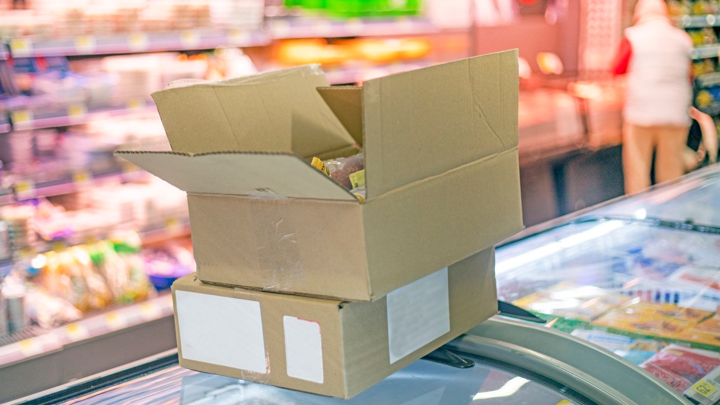 Boxes stacked on top of an island freezer at a grocery store.