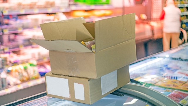 Boxes stacked on top of an island freezer at a grocery store.