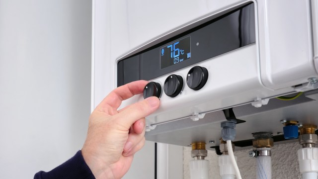 A hand adjusting temperature controls on a boiler.