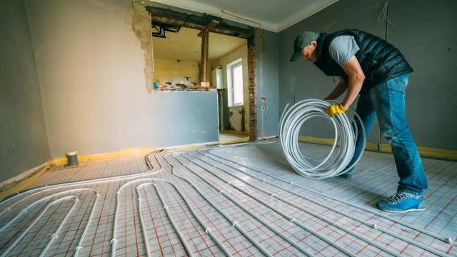 A person installing heating pipes.
