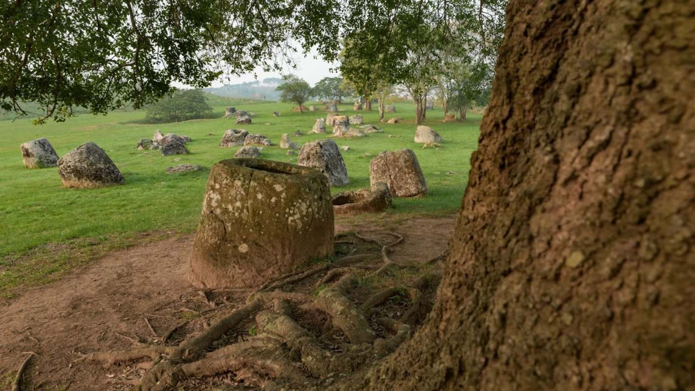 Large stone jars dotted across a grassy landscape.