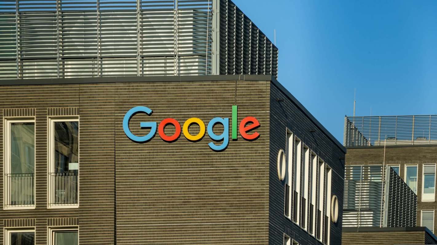The Google logo displayed prominently on a modern building's facade against a clear blue sky.