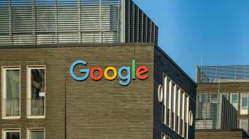 The Google logo displayed prominently on a modern building's facade against a clear blue sky.