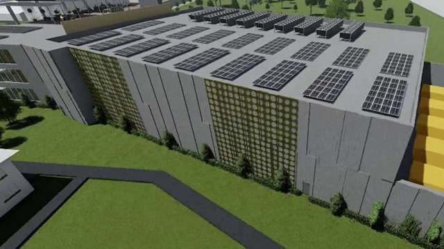 A modern building with solar panels on the roof and greenery along the sides.