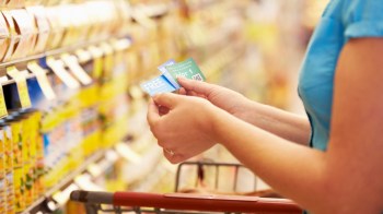 A person shopping with coupons in a grocery store.