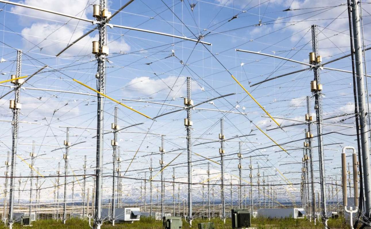 An array of tall antennas and intricate wiring under a blue sky with scattered clouds.